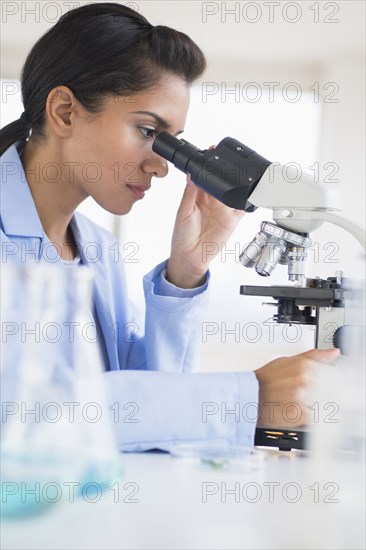 Hispanic scientist using microscope in laboratory