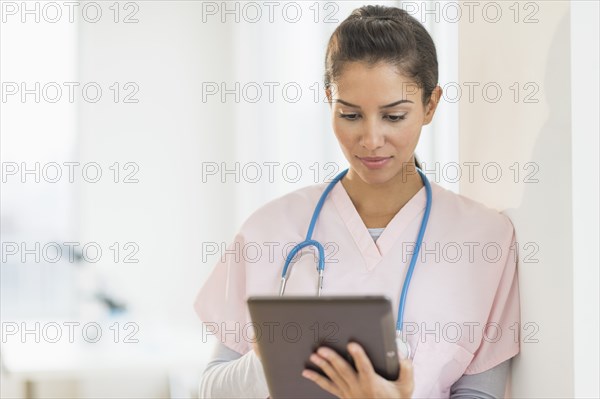 Hispanic nurse using digital tablet in hospital