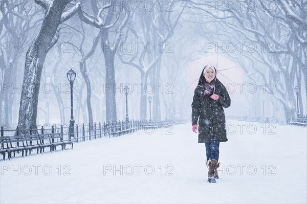 Asian woman walking in snowy Central Park