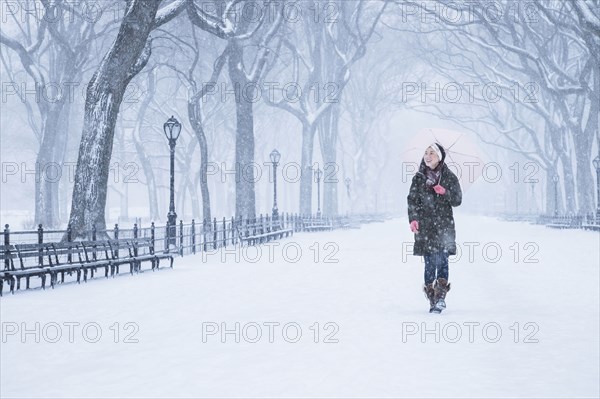 Asian woman walking in snowy park