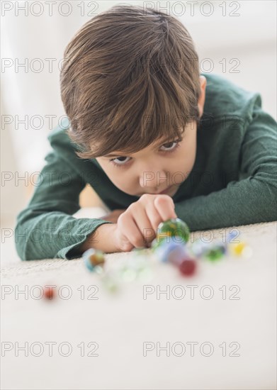 Hispanic boy playing with marbles on floor