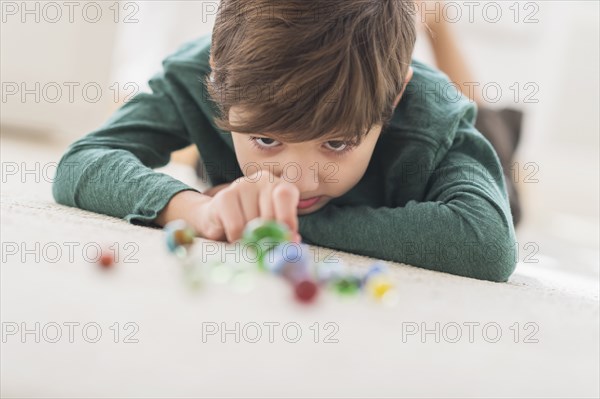 Hispanic boy playing with marbles on bedroom floor