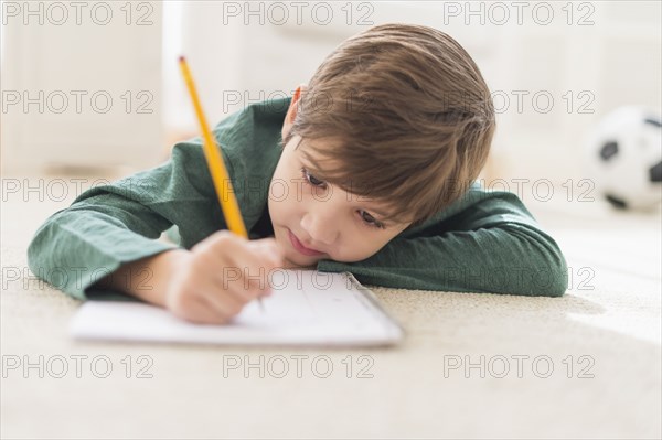 Hispanic boy doing homework on floor