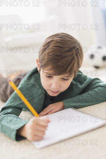 Hispanic boy doing homework on floor