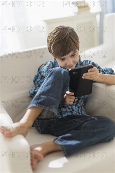 Hispanic boy using digital tablet in armchair