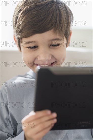 Hispanic boy using digital tablet on sofa