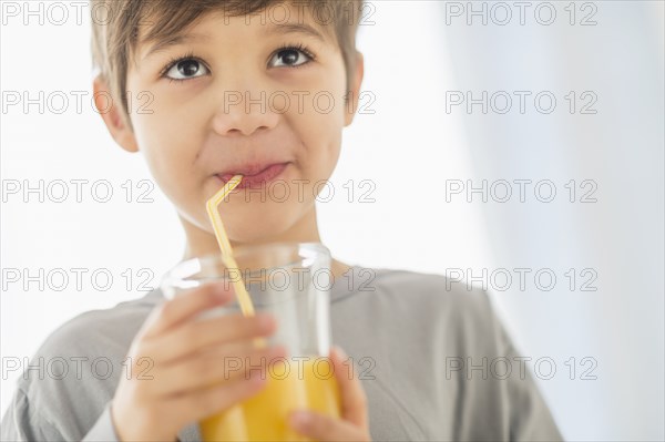 Hispanic boy drinking juice with straw