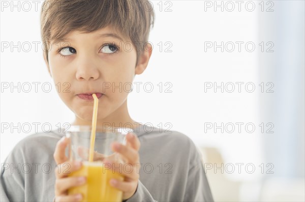 Hispanic boy drinking juice with straw