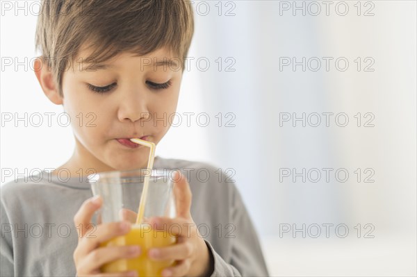 Hispanic boy drinking juice with straw