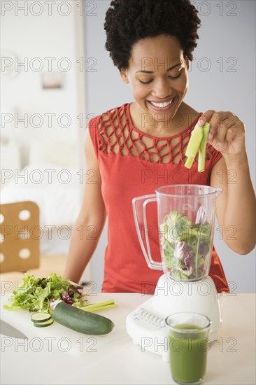 Black woman making green smoothies in blender