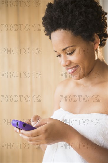 Black woman in towel using cell phone