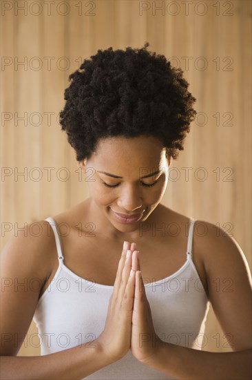 Close up of serene Black woman with hands in prayer position