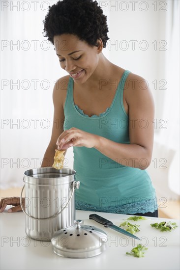 Black woman placing apple core in compost bucket