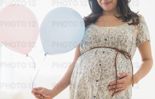 Pregnant Hispanic woman carrying balloon