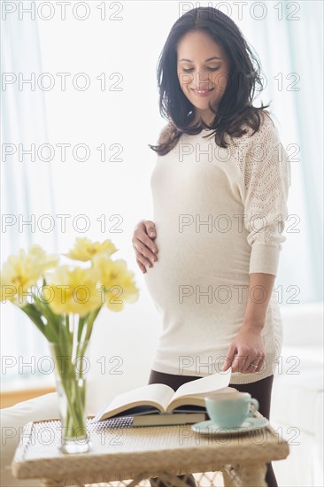 Pregnant Hispanic woman reading book