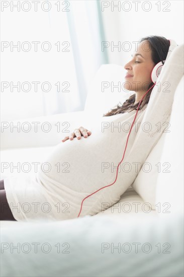 Pregnant Hispanic woman listening to headphones