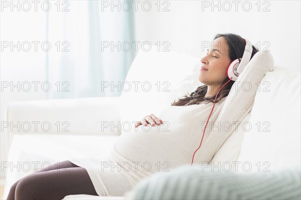 Pregnant Hispanic woman listening to headphones