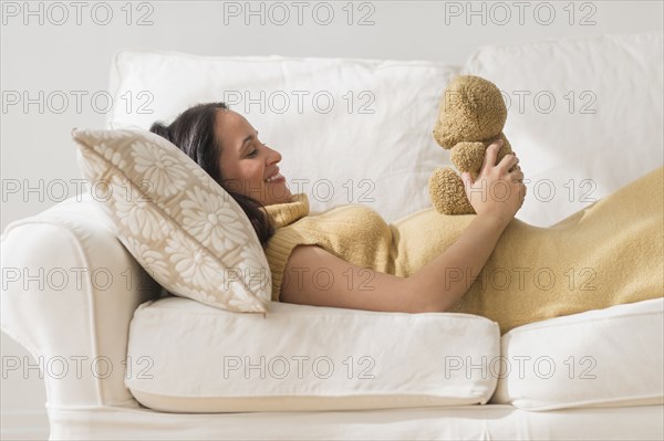 Pregnant Hispanic woman admiring teddy bear