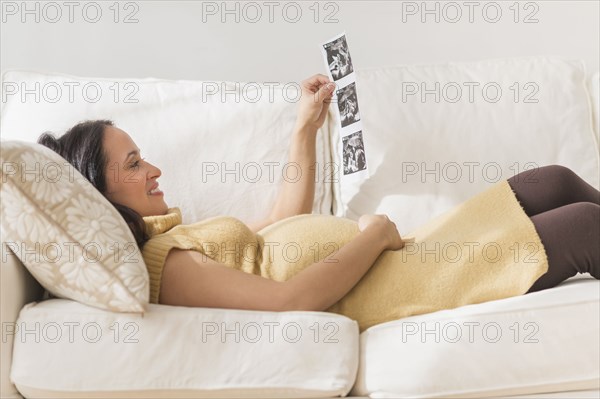 Pregnant Hispanic woman admiring ultrasound photos