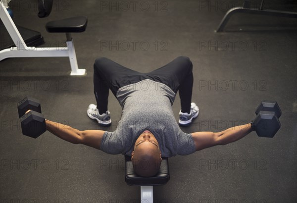 Black man lifting weights in gym