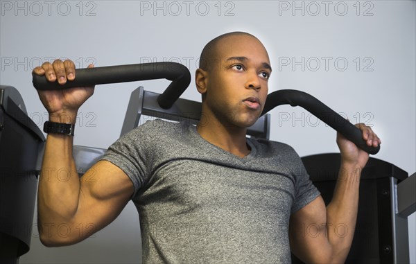Black man lifting weights in gym