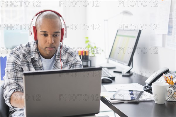 Black businessman listening to headphones in office