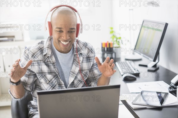 Black businessman listening to headphones in office