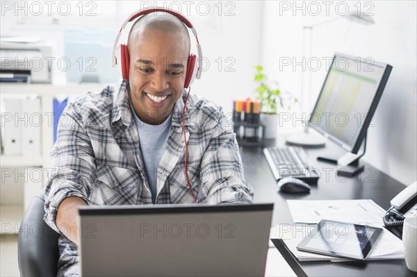 Black businessman listening to headphones in office