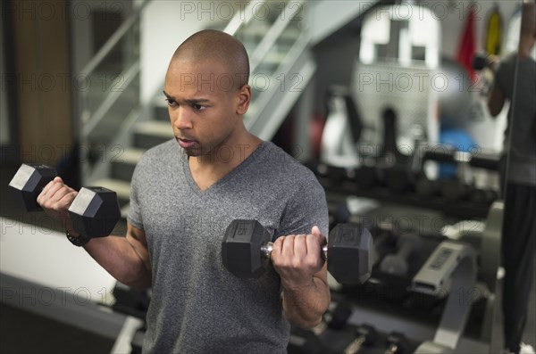 Black man lifting weights in gym