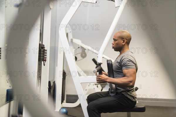 Black man lifting weights in gym