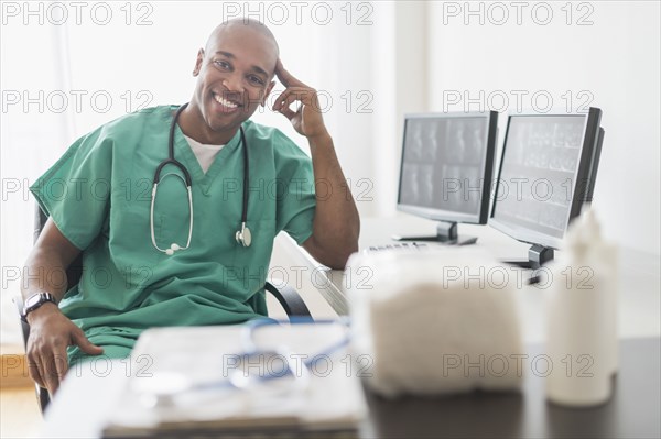 Black doctor smiling at computer in office