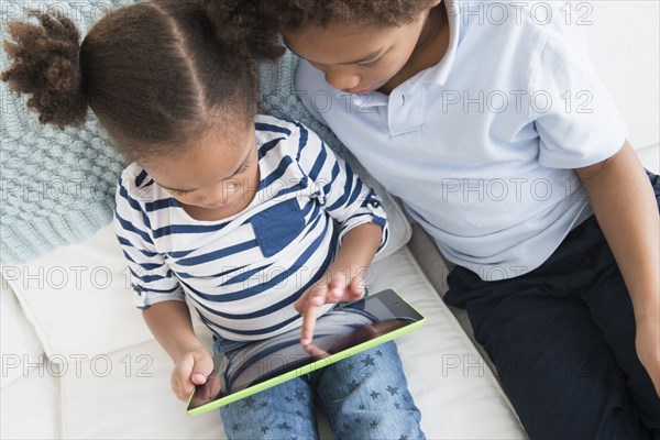 Black children using digital tablet together