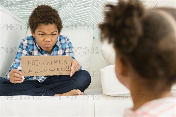 Black boy holding No girls allowed' sign for sister