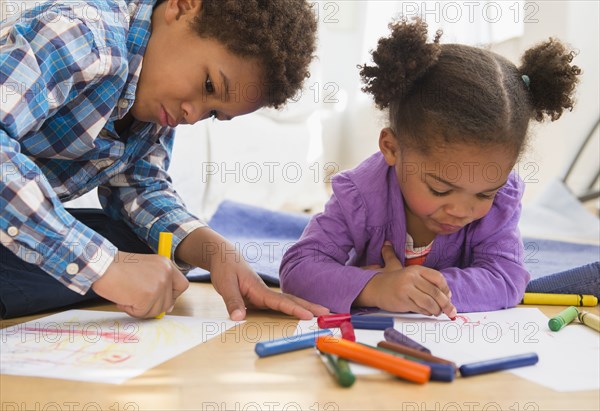 Black children coloring on living room floor