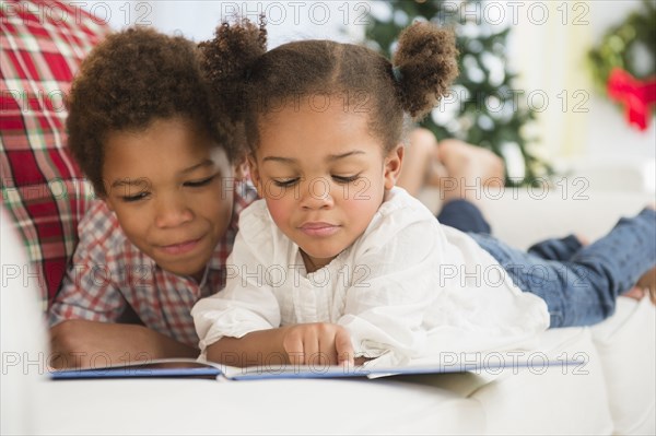 Black children reading together on sofa