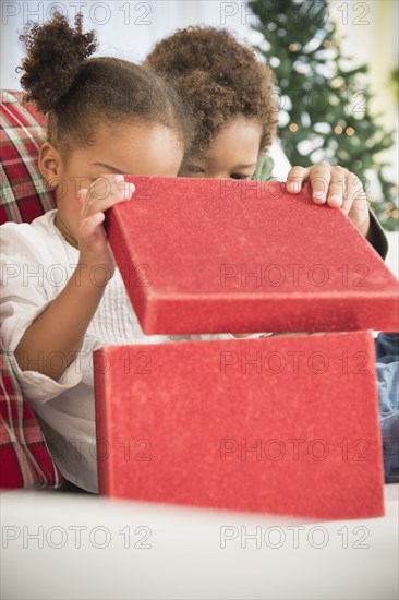 Black children opening Christmas gift on sofa