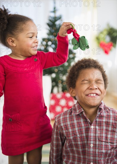 Black children playing with mistletoe in living room