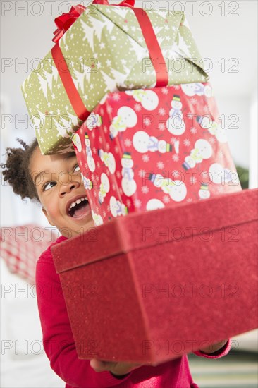 Black girl carrying stack of Christmas presents