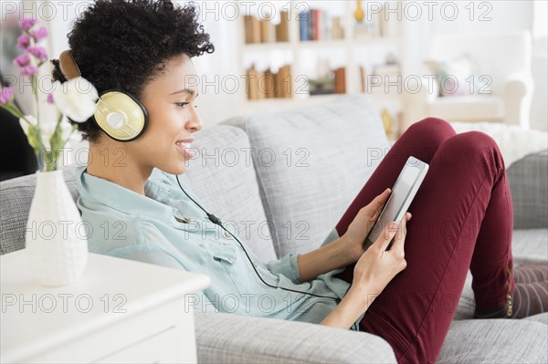 Black woman listening to headphones on sofa