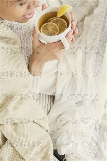 Black woman drinking cup of tea with lemon