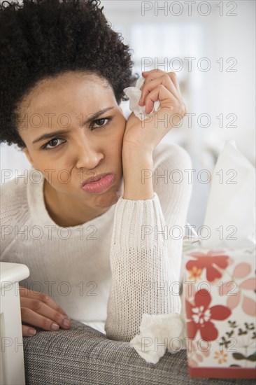 Black woman wiping her nose with tissues