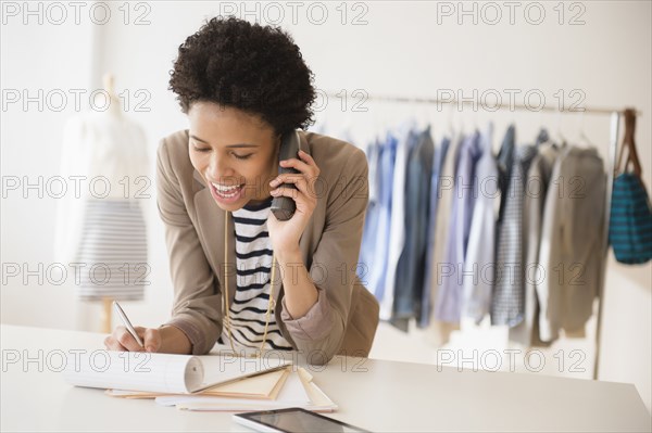 Black dressmaker talking on phone in studio