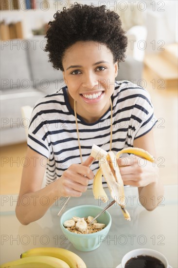 Black woman eating fruit and cereal for breakfast