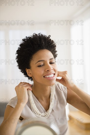Black woman trying on necklace in mirror