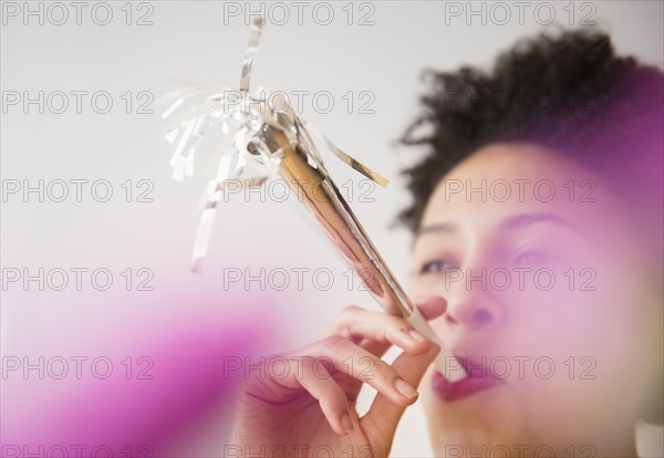 Black woman blowing noisemaker at party