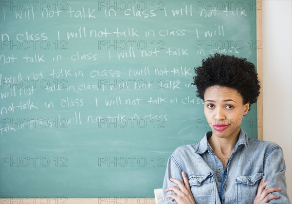 Black woman writing lines on chalkboard