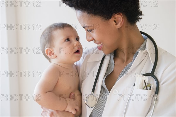 Smiling doctor holding baby