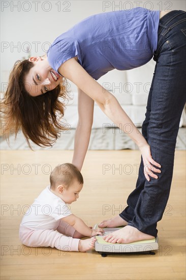 Mother with new baby standing on scale