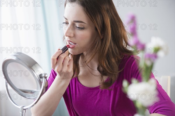 Woman applying makeup in mirror