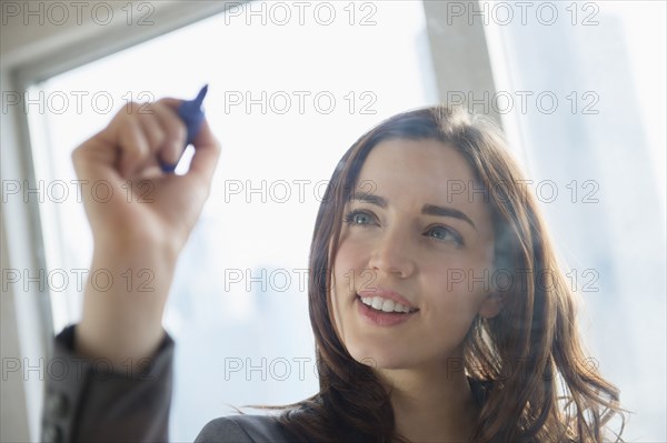 Businesswoman writing on glass